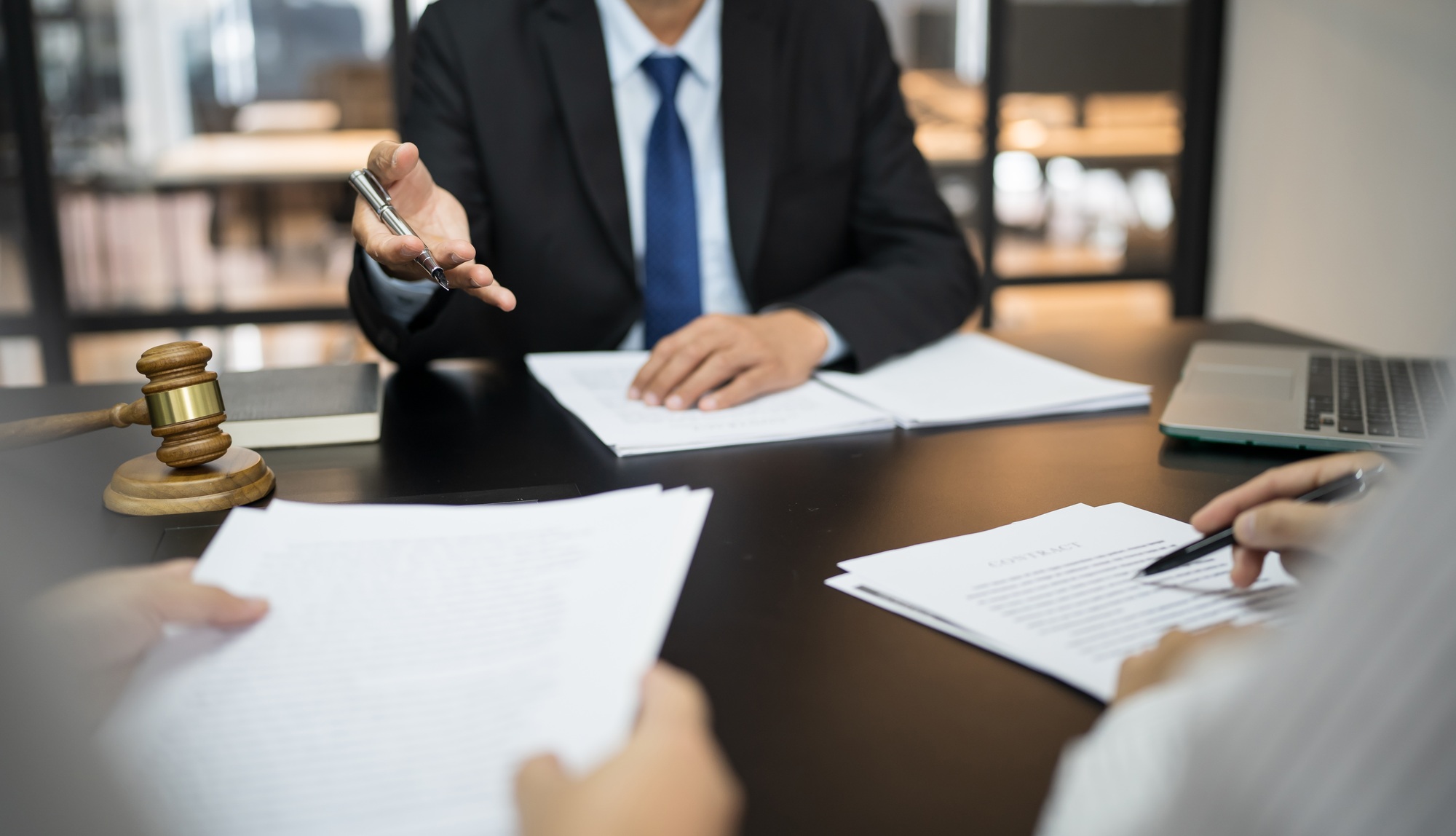 Legal counsel presents to the client a signed contract with gavel and legal law.